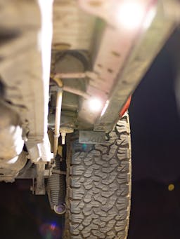 Rock Lights mounted underneath a vehicle chassis to illuminate the ground below.